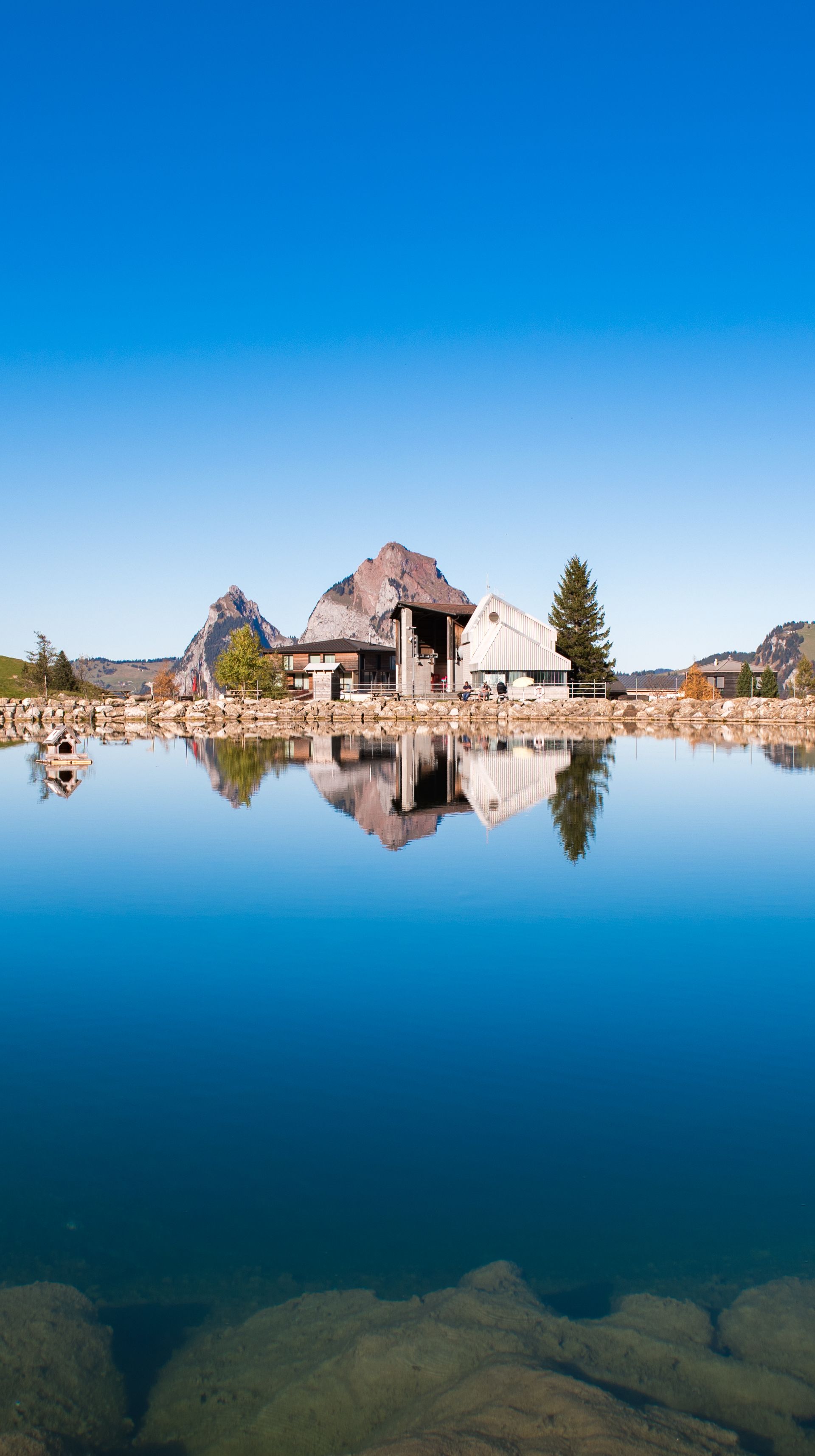 Mountain lake reflecting the surrounding landscape and chapel in an alpine setting.